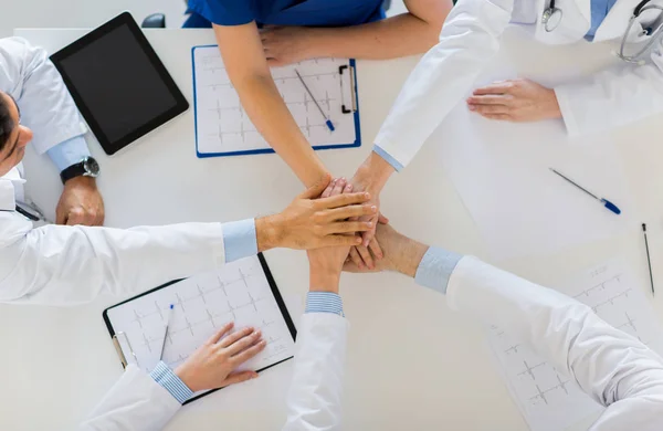 Grupp läkare håller händerna ihop vid bord — Stockfoto