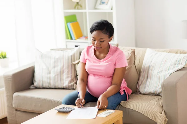 Pregnant woman with bills and money at home — Stock Photo, Image