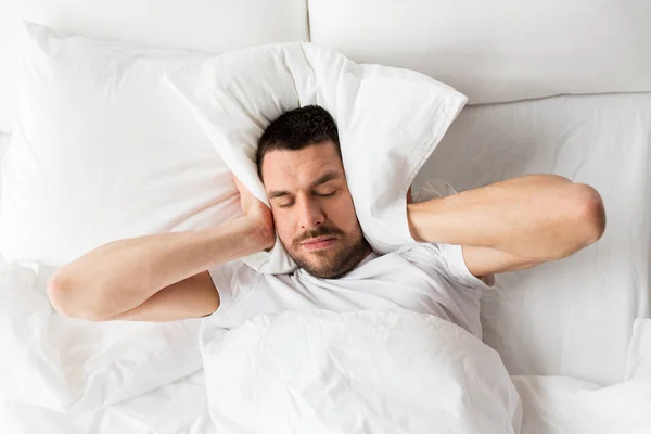 Muž v posteli s polštářem trpí hlukem — Stock fotografie