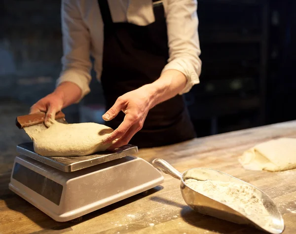 Chef or baker weighing dough on scale at bakery — Stock Photo, Image