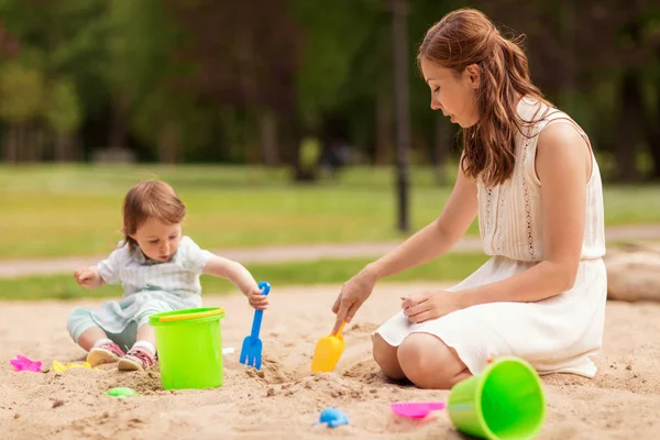 Mutlu anne ve bebek kız kum havuzunda oynamayı — Stok fotoğraf