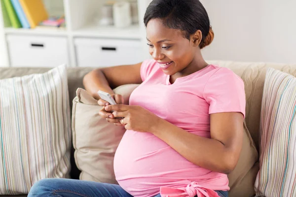 Szczęśliwa kobieta w ciąży ze smartfonem w domu — Zdjęcie stockowe