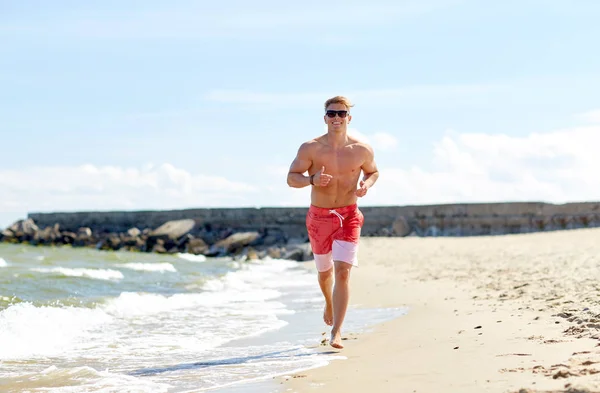 Glücklicher Mann läuft am Sommerstrand entlang — Stockfoto