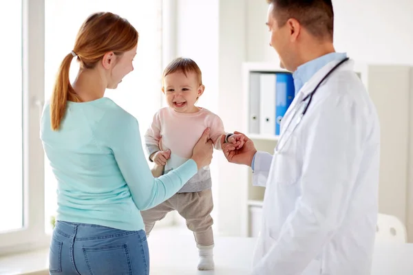 Happy woman with baby and doctor at clinic — Stock Photo, Image