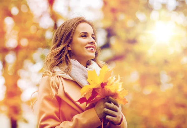 Hermosa mujer con hojas de arce en el parque de otoño — Foto de Stock