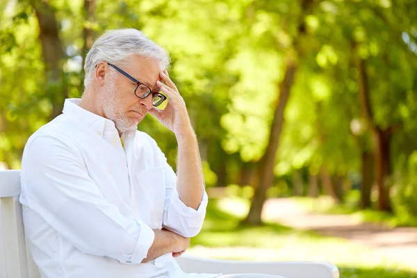 Doordachte senior man zit in het park van de zomer — Stockfoto