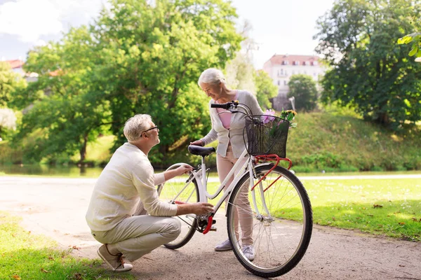 Feliz casal sênior com bicicleta no parque de verão — Fotografia de Stock