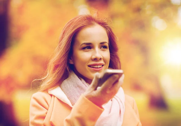 Frau nimmt Stimme auf Smartphone im Herbstpark auf — Stockfoto