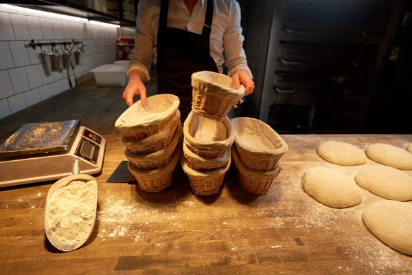 Panadero con cestas para la masa que sube en la panadería —  Fotos de Stock