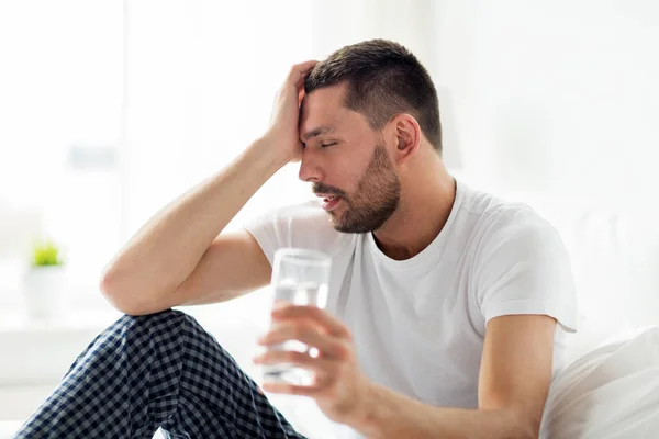 Hombre en la cama con vaso de agua en casa —  Fotos de Stock