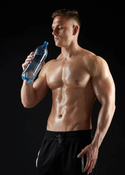 Young man or bodybuilder with bottle of water — Stock Photo, Image