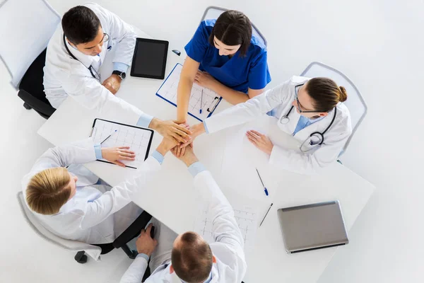 Groep van artsen die hand in hand samen aan tafel — Stockfoto