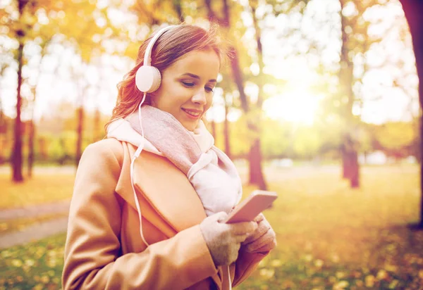Mujer con smartphone y auriculares en el parque de otoño — Foto de Stock