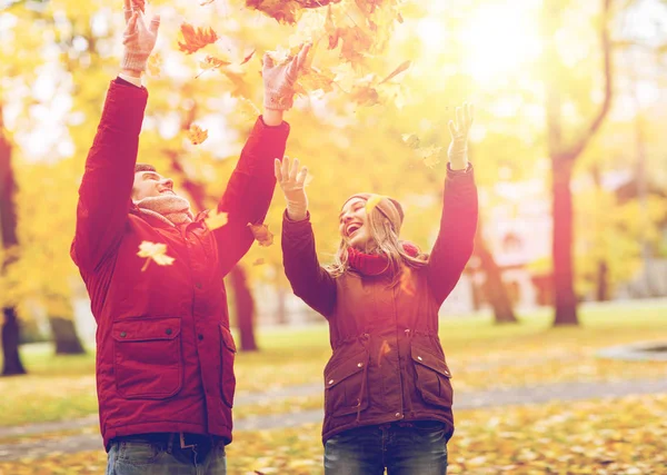 公園で秋を投げて幸せな若いカップルを葉します。 — ストック写真