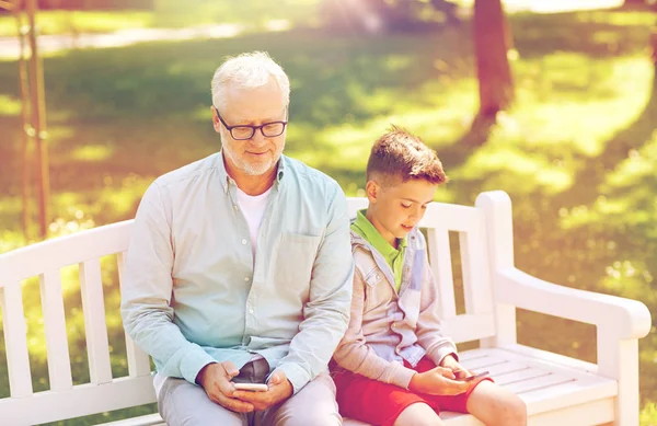 Old man and boy with smartphones at summer park — Stock Photo, Image