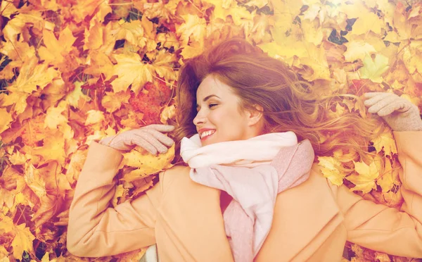 Hermosa mujer feliz acostada en hojas de otoño — Foto de Stock