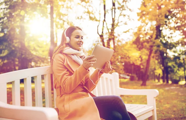 Mujer con tablet PC y auriculares en el parque de otoño —  Fotos de Stock