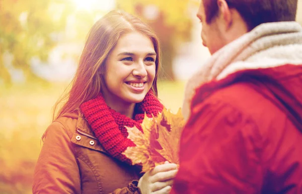 Happy couple with maple leaves in autumn park — Stock Photo, Image