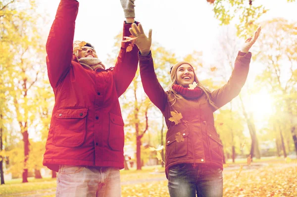 Happy young couple throwing autumn leaves in park — Stock Photo, Image