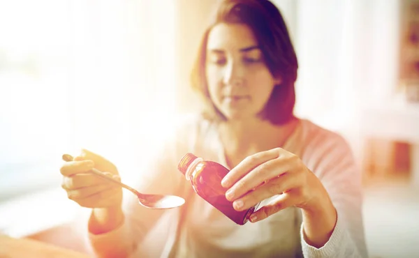 Vrouw gieten medicatie van de fles op de lepel — Stockfoto