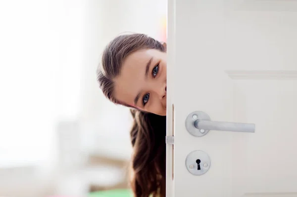 Felice sorridente bella ragazza dietro la porta di casa — Foto Stock