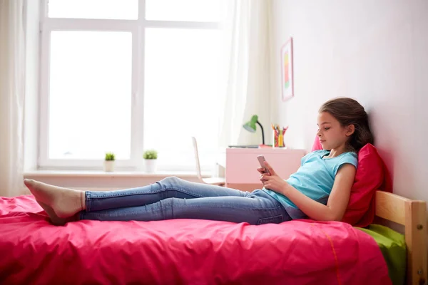 Dívka SMS nebo hrát hru na smartphone doma — Stock fotografie