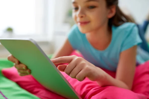 Sorridente ragazza con tablet pc sdraiato sul letto a casa — Foto Stock