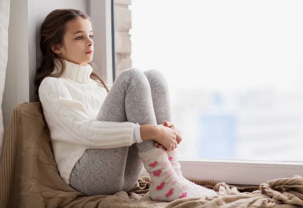 Triste fille assis sur le seuil à la fenêtre de la maison en hiver — Photo