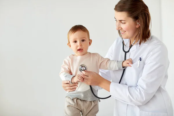 Médico feliz com estetoscópio e bebê na clínica — Fotografia de Stock