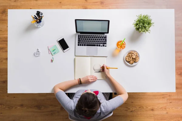 Vrouw met laptop tekening in notitieblok op kantoor — Stockfoto