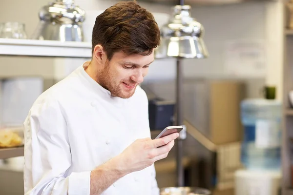 Cozinheiro chef com smartphone na cozinha do restaurante — Fotografia de Stock