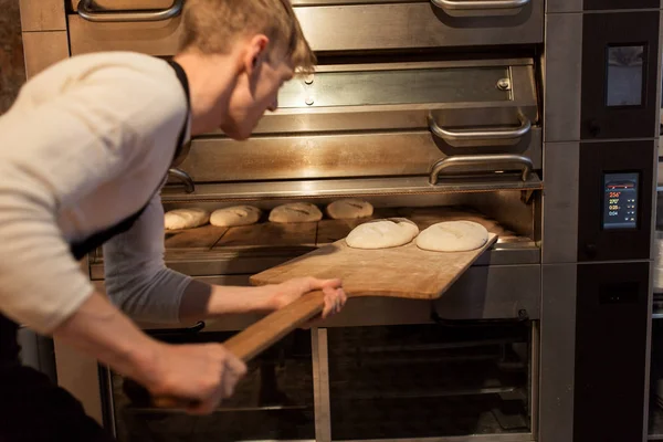 Bäcker legt Teig in Brotbackofen beim Bäcker — Stockfoto