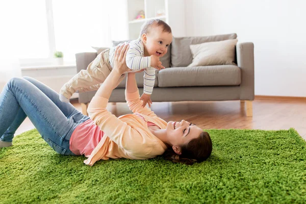 Feliz joven madre jugando con el bebé en casa — Foto de Stock