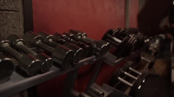 Homem tomando halteres de rack de armazenamento no ginásio — Vídeo de Stock