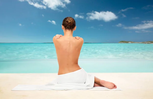 Mooie vrouw in de handdoek met blote rug op strand — Stockfoto