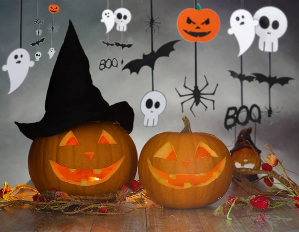 Carved pumpkins in witch hat and halloween garland — Stock Photo, Image