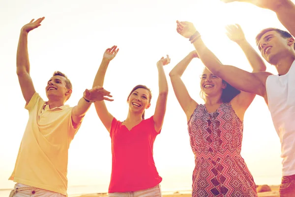 Amigos sonrientes bailando en la playa de verano — Foto de Stock