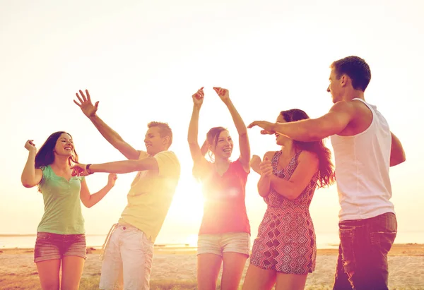 Lächelnde Freunde tanzen am Sommerstrand — Stockfoto