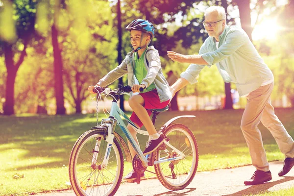 Farfar och pojke med cykel på sommaren park — Stockfoto