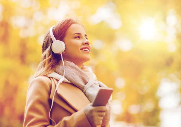 Mujer con smartphone y auriculares en el parque de otoño — Foto de Stock