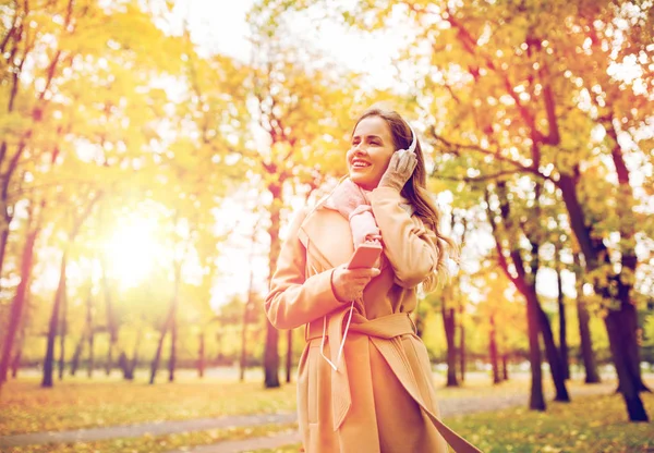 Mujer con smartphone y auriculares en el parque de otoño — Foto de Stock