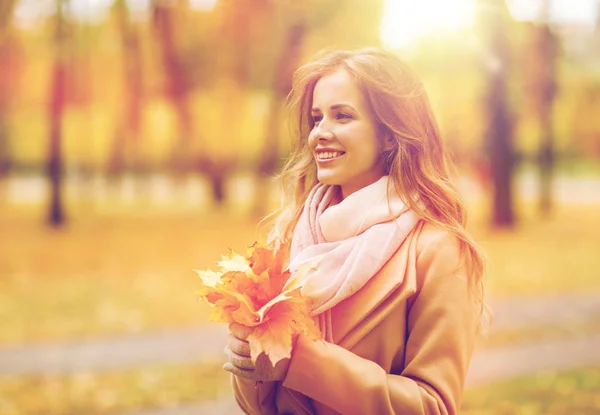 Hermosa mujer con hojas de arce en el parque de otoño — Foto de Stock