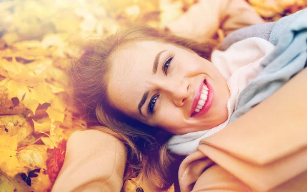 Hermosa mujer feliz acostada en hojas de otoño —  Fotos de Stock