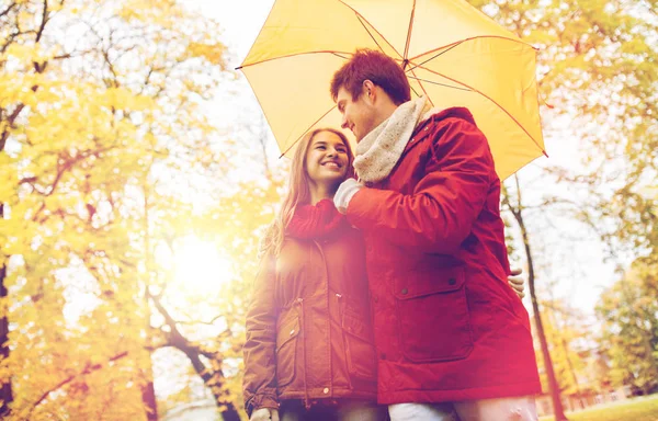 Smiling couple with umbrella in autumn park — Stock Photo, Image