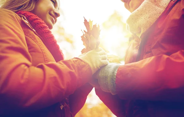 Close up de casal feliz com folhas de bordo de outono — Fotografia de Stock