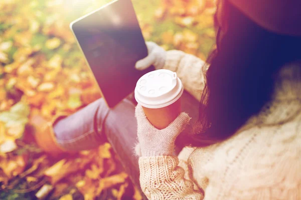 Vrouw met tablet pc en koffie in de herfst park — Stockfoto