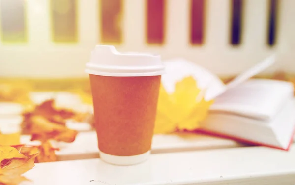 Bebida de café en taza de papel en el banco en el parque de otoño — Foto de Stock