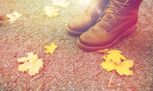 Pés femininos em botas e folhas de outono — Fotografia de Stock