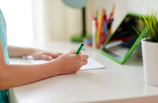 Girl with tablet pc writing to notebook at home — Stock Photo, Image