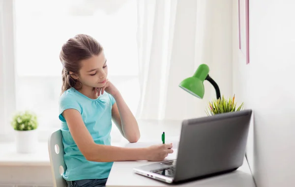 Chica con la escritura del ordenador portátil a la libreta en casa —  Fotos de Stock